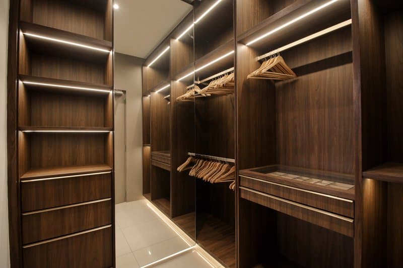 Walk-in wardrobe with dark wood finish and LED strip lighting